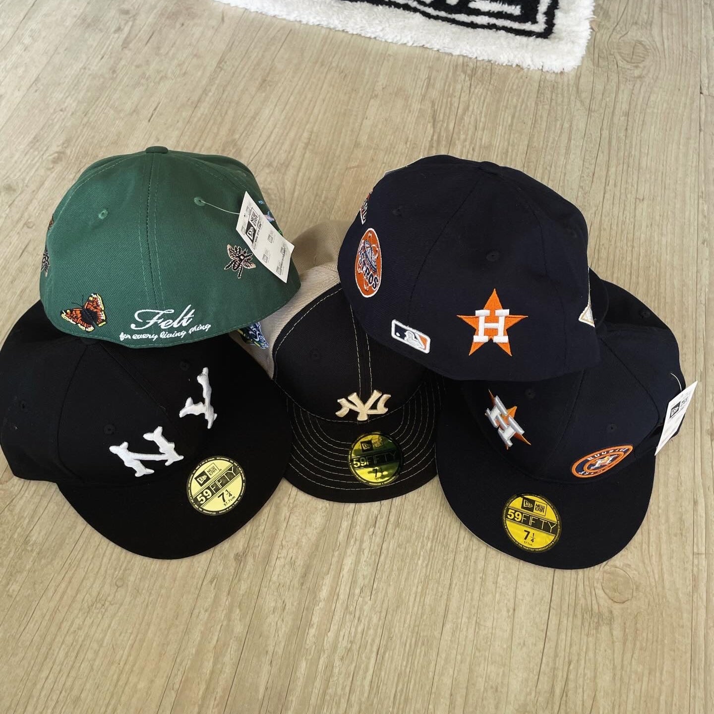 Collection of baseball caps with logos on a wooden surface, featuring a 'Grail' brand towel in the background.